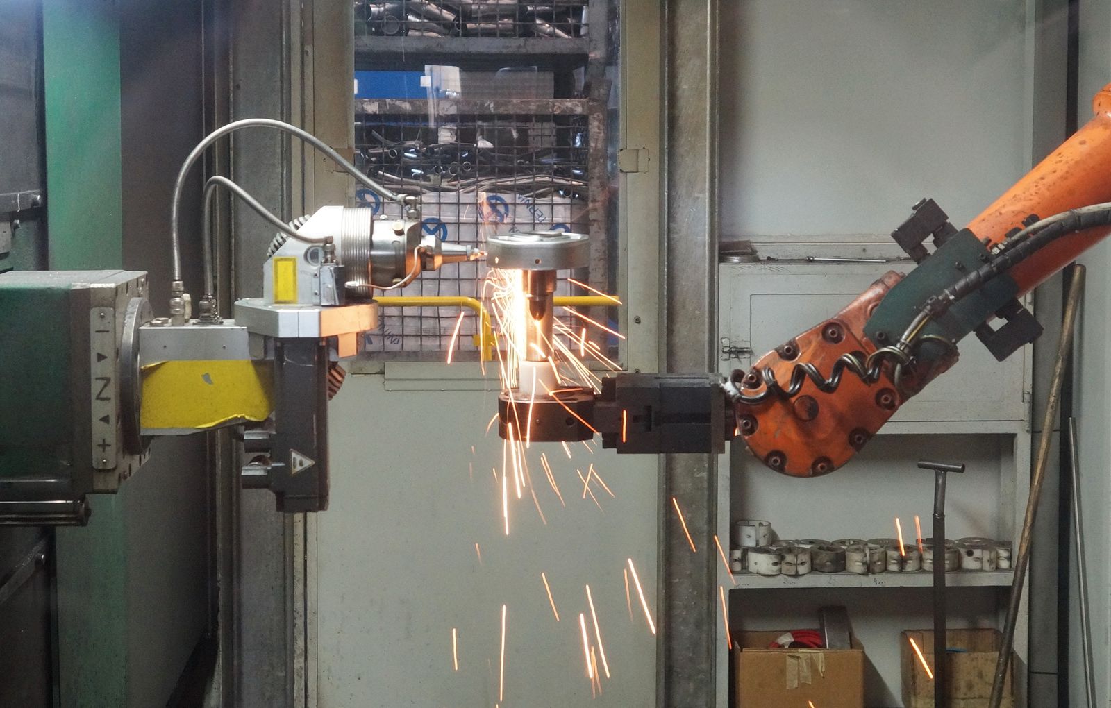 An industrial robot arm welding a part on a factory floor